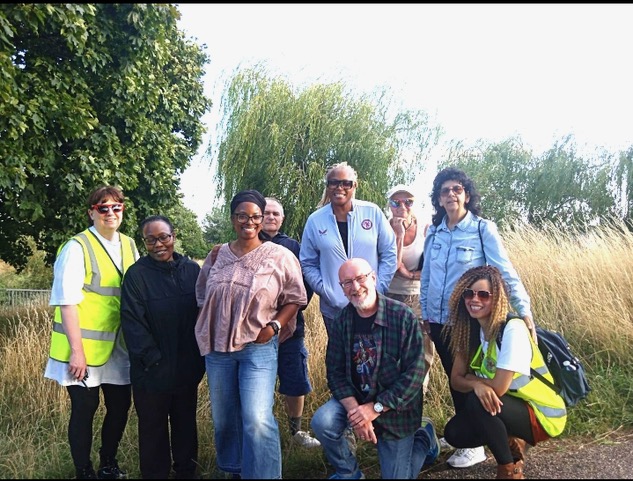 Group of people standing in front of a field, smiling at the camera. 